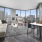 Spacious and well lit living room with wood flooring, large windows and open access to the kitchen
