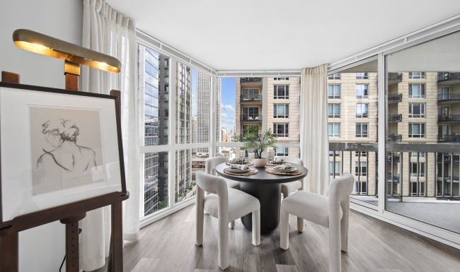 Spacious and well lit living room with wood flooring, large windows and open access to the kitchen.